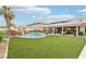Lush backyard featuring a pool, rock waterfall, outdoor kitchen, and verdant lawn at 9410 Stone Castle Way, Las Vegas, NV 89123