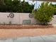 Backyard landscape featuring a stone wall, desert landscaping, a mature tree, and garden decor at 9600 Pacific View Dr, Las Vegas, NV 89117