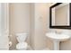 A clean half bathroom featuring pedestal sink, mirror, and white toilet at 1311 Rolling Sunset St, Henderson, NV 89052