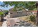 View of a single-story house with chain link fencing and a paved driveway, some landscaping, and a large tree providing shade at 2528 Sunrise Ave, Las Vegas, NV 89101