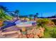 Landscaped backyard with hot tub, palm trees, and decorative rockwork create a private oasis at 301 E Longacres Dr, Henderson, NV 89015
