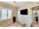 Bedroom featuring a large window with shutter blinds, a mounted television, and an adjacent home office at 3307 Forestina Ct, Las Vegas, NV 89122