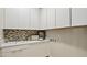 Well-lit laundry room with white cabinets, mosaic backsplash, sink, and ample counter space at 344 Tigullio Ave, Henderson, NV 89011