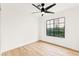 Minimalist bedroom with hardwood flooring, a black ceiling fan, and a large window at 4856 Fiesta Lakes St, Las Vegas, NV 89130