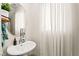 Cozy bathroom with a pedestal sink, decorative mirror, sheer curtains, and neutral decor at 5674 Moccasin Point St, Las Vegas, NV 89148