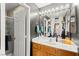 Elegant bathroom featuring a wood vanity, decorative mirror, modern lighting, and glass-enclosed shower at 5674 Moccasin Point St, Las Vegas, NV 89148