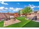 Well maintained backyard with artificial turf, a built-in fire pit, lounge area, and hot tub at 6187 Novelty St, Las Vegas, NV 89148