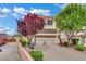 Two-story house features a two-car garage and a well-manicured lawn with mature trees in the front yard at 6187 Novelty St, Las Vegas, NV 89148