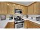 Close-up of the kitchen with stainless steel gas range, microwave, and oak cabinets at 6187 Novelty St, Las Vegas, NV 89148