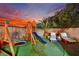 An ideal outdoor play area featuring a swing set and lounging chairs surrounded by palm trees and artificial grass at 6187 Novelty St, Las Vegas, NV 89148