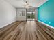 Spacious living room featuring wood floors, bright accent wall, and sliding glass door to the backyard at 6312 Conlon St, North Las Vegas, NV 89081