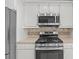 Updated kitchen featuring stainless steel appliances, white cabinets, and tile backsplash at 664 Peachy Canyon Cir # 103, Las Vegas, NV 89144