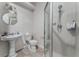 Updated bathroom featuring tiled shower, sink, toilet, large mirror and updated light fixture at 7720 W Agate Ave, Las Vegas, NV 89113