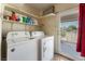 Well-lit laundry room with washer, dryer, shelves, and backyard access at 7720 W Agate Ave, Las Vegas, NV 89113