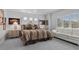 Bright bedroom featuring a queen-sized bed, neutral walls, carpet flooring, and a window-side sofa at 8083 Shadowvale Dr, Las Vegas, NV 89147