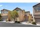 Two-story home with tan exterior and attached garage, highlighted by a mature tree and well-kept landscaping at 8448 Quarentina Ave, Las Vegas, NV 89149