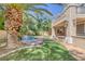 Exterior view of a backyard featuring a built-in grill, water feature, and lush artificial grass at 8825 Rozetta Ct, Las Vegas, NV 89134