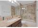 Well-lit bathroom with a shower over tub, wood vanity, granite countertop, and sleek sliding glass doors at 8825 Rozetta Ct, Las Vegas, NV 89134