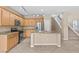 Modern kitchen features wood cabinetry, stainless steel appliances, and an island overlooking a naturally lit living room and staircase at 9709 Fast Elk St, Las Vegas, NV 89143