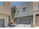 Contemporary multi-level townhome shows stucco, a two-car garage, and landscaped entry in desert community at 11377 Gravitation Dr, Las Vegas, NV 89135