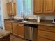 Well-lit kitchen featuring stainless steel dishwasher, granite counters, and wood cabinets at 1146 Olivia Pkwy, Henderson, NV 89011