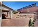 Backyard boasts rock landscaping, small trees and shrubbery, covered patio with brick, and brick wall at 15 Santo Mio Ct, Henderson, NV 89011