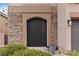 Elegant front entrance with a unique arched door, stone accents, and lush landscaping enhancing curb appeal at 176 Dunblane St, Henderson, NV 89012