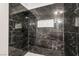 Modern bathroom with black marble tiled shower with built-in niche and dark fixtures at 1804 Michael Ct, Henderson, NV 89014