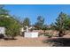 Desert backyard with trees, plants, rocks, and decorative white square structure at 2188 Cumberland Hill Dr, Henderson, NV 89052