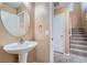 Powder room featuring pedestal sink with oval mirror and access to carpeted stairs at 3141 Diamond Crest Ln, Henderson, NV 89052