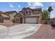 Exterior view of a two-story home with a long driveway and neutral tones in a desert landscape at 5228 Giallo Vista Ct, North Las Vegas, NV 89031