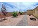 Side yard featuring a paved path, rock landscaping, and desert plantings at 5528 Eleganza Ave, Pahrump, NV 89061