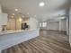 Open living space with island seating and wood-look floors flowing into living area at 6638 Babys Tear Pl, Las Vegas, NV 89148