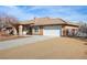 A single-story home has a desert landscape, a tile roof, and a long, paved driveway leading to the garage at 6781 Southgate St, Pahrump, NV 89061
