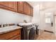 Spacious laundry room with washer, dryer, sink and wood cabinets and tile floors at 6781 Southgate St, Pahrump, NV 89061