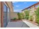 Private patio with lush landscaping, including flowering bushes and leafy trees at 690 Ambling Gait Ave, Henderson, NV 89015