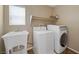 The laundry room has a sink, a washing machine, and a dryer that receives natural light from the window at 7028 Weavers Pl, North Las Vegas, NV 89084