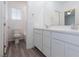 Bright bathroom with double vanity, white cabinets, and wood-look floors at 835 Aurelie Ridge St, Henderson, NV 89011
