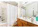 Bathroom featuring bathtub-shower, wood cabinets and a large mirror, providing functionality and style at 9330 W Maule Ave # 138, Las Vegas, NV 89148