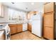 Cozy kitchen featuring warm wood cabinets, white appliances and a window providing natural light at 9330 W Maule Ave # 138, Las Vegas, NV 89148