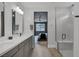 Bright bathroom boasts a double vanity, frameless glass shower, and a view to the stylish primary bedroom at 9617 Sard Ln, Las Vegas, NV 89143