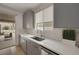 Modern kitchen sink with gray cabinets, white countertop, and access to patio with outdoor seating at 9789 Twilight Moon Ave, Las Vegas, NV 89148