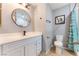 Modern bathroom with white vanity, round mirror, toilet, shower with teal curtain, and neutral paint at 1012 Greystone Dr, Las Vegas, NV 89108
