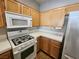 Kitchen featuring wooden cabinets, white appliances, tile countertops, and ample storage space at 10231 Deerfield Beach Ave # 104, Las Vegas, NV 89129