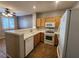 Well-lit kitchen featuring wooden cabinets, white appliances, tile countertops, and a pass-through to the dining area at 10231 Deerfield Beach Ave # 104, Las Vegas, NV 89129