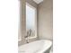 Modern bathroom featuring a freestanding tub with chrome fixtures and textured beige tiling at 11453 Glowing Sunset Ln, Las Vegas, NV 89135