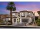 Elegant two-story home featuring a tile roof, a palm tree, and a driveway leading to attached garages at 11453 Glowing Sunset Ln, Las Vegas, NV 89135