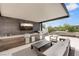 Outdoor kitchen with sleek grill, white seating, and mounted television at 11453 Glowing Sunset Ln, Las Vegas, NV 89135