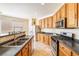 View of the kitchen featuring wooden cabinetry, stainless steel appliances, and black countertops at 11894 Snow Bank St, Las Vegas, NV 89183