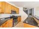 Kitchen featuring wood cabinets, stainless steel appliances, and black countertops at 11894 Snow Bank St, Las Vegas, NV 89183